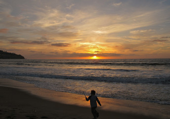 Fototapeta na wymiar Toddler Playing on the Beach Silhouette at Torrance Beach During Sunset, California