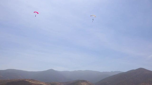Elite military forces and paratroopers skydive onto and land in a field during training operations.