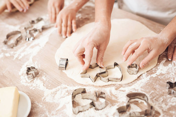 Female and children's hands make form for biscuits with help of baking molds.