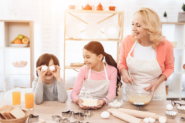 Young grandmother and granddaughter are laughing at little boy who makes face.