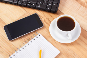Mobile phone with notepad for writing notes and cup of coffee, using electronics concept