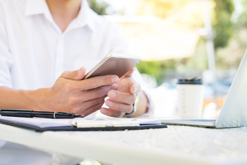 Businessman On Park Bench texting on smartphone outdoor in the garden