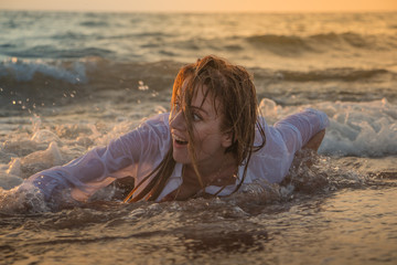 Girl rests and has fun in sea wave at sunset