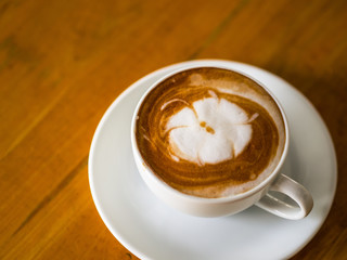 Hot coffee latte art on wooden table.