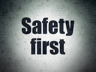 Safety concept: Painted black word Safety First on Digital Data Paper background