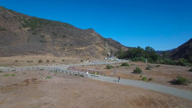 Aerial footage following a man riding an electric unicycle down a road in California.
