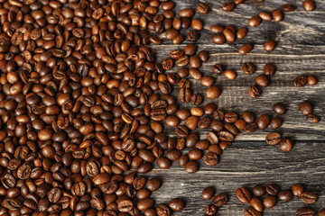 A coffee cup with coffee beans on an old wooden table. Fried coffee beans on a wooden background. Viewing from above.