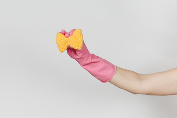 Close up of female hand in pink gloves holds and squeezes yellow-orange sponge for cleaning and washing dishes isolated on white background. Cleaning supplies concept. Copy space for advertisement