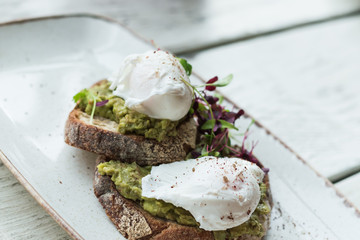 Avocado with poached eggs on toast in trendy hipster restaurant high end