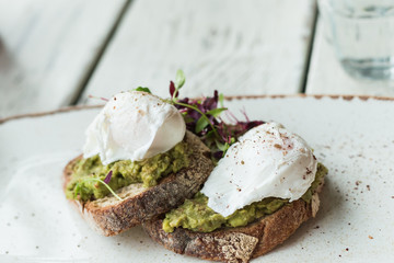 Avocado with poached eggs on toast in trendy hipster restaurant high end
