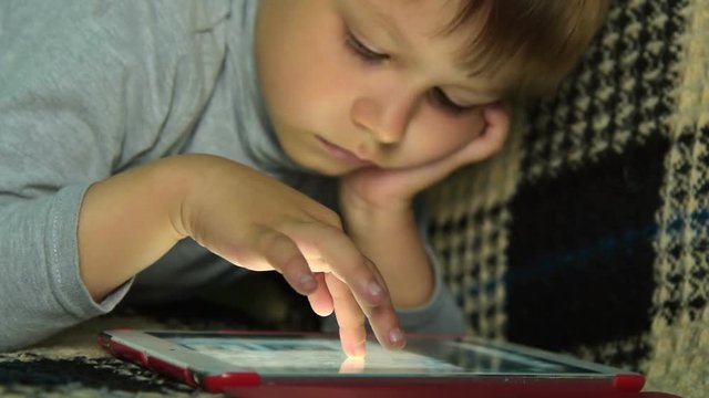 Speed-up shot of four year old child scrolling the apps on tablet computer in search of what to play. Home leisure with touch pad
