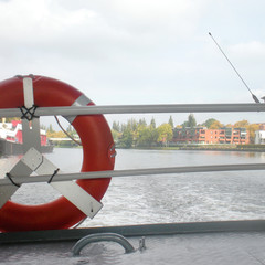 Red lifebuoy on a tourist boat on the background of water