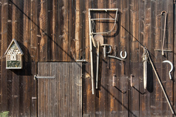 old rural tools hanging on a wooden barn door as decoration