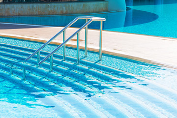 Blue swimming pool with stair at luxery hotel