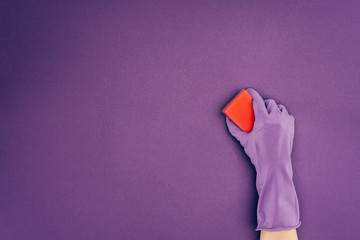 cropped image of woman holding washing sponge in protective glove isolated on violet