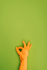 cropped image of woman showing ok sign in protective rubber glove isolated on green