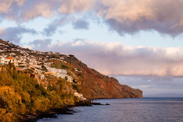 Small mountain houses located on a coastline in front of the ocean during the golden hour in Funchal, Madeira, Portugal
