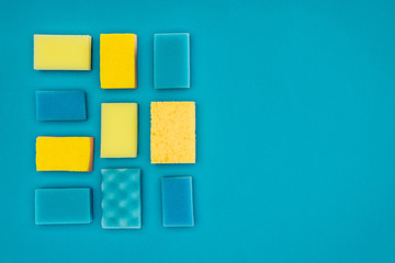 top view of yellow and blue washing sponges isolated on blue