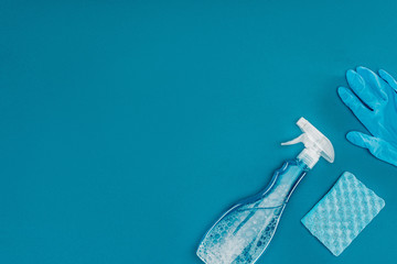 top view of spray bottle and rubber glove with washing sponge isolated on blue