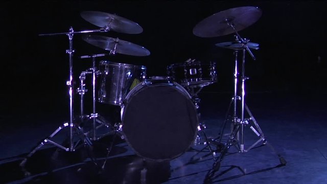 A drum set sits on a dark stage.