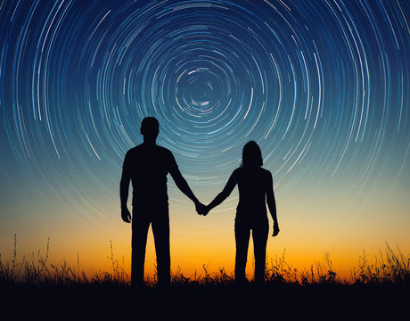 Silhouette of young couple under stars. The concept on the theme of love, earth day holiday. Elements of this image furnished by NASA.