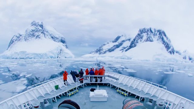 A POV time lapse shot of a ship bow, icebergs and tourists passing through Lemaire Channel Antarctica.