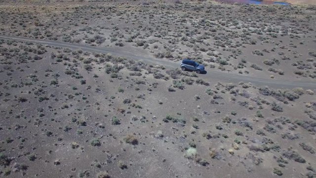 Aerial above a 4WD traveling on a dirt road in the Mojave Desert with the Sierra Nevada mountains distant.