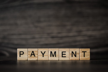 the word payment, consisting of light wooden square panels on a dark wooden background