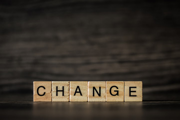 the word change, consisting of light wooden square panels on a dark wooden background