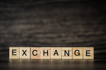 the word exchange, consisting of light wooden square panels on a dark wooden background