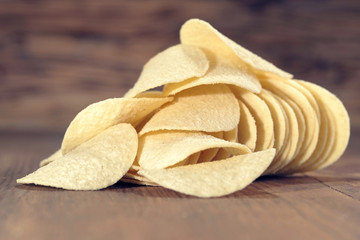 Crispy potato chips in wooden background. Salted potato chips