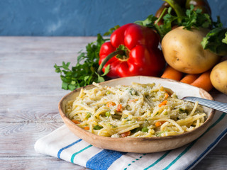 Spaghetti cooked in vegetable broth sauce on rustic wooden background. Healthy lunch