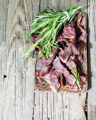 jerked meat, cow, deer, wild beast or biltong in wooden bowls on a rustic table, selective focus