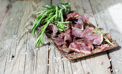 jerked meat, cow, deer, wild beast or biltong in wooden bowls on a rustic table, selective focus