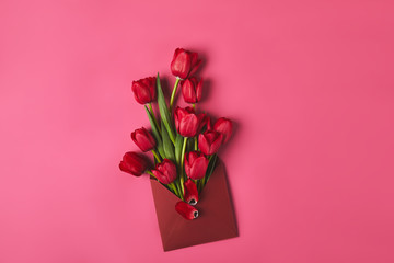 top view of red tulips in envelope on pink, mothers day concept