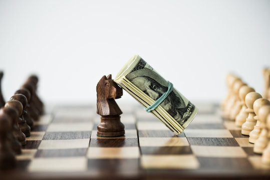 Close up view of chess board with cash and black knight isolated on white