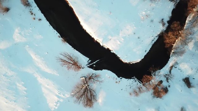 Flying over small frozen river. Ice and snow. Aerial view landscape