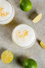 Peruvian, Mexican, Chilean traditional drink pisco sour liqueur, with fresh lime, on gray stone table, copy space top view