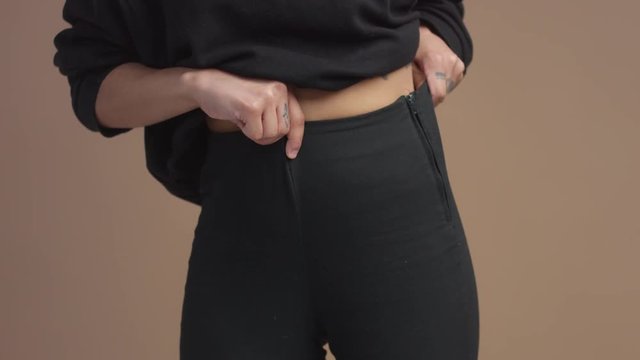 closeup of woman's waist and hand touching a pants