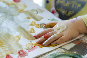 A little girl paints with brush and paints on a piece of paper