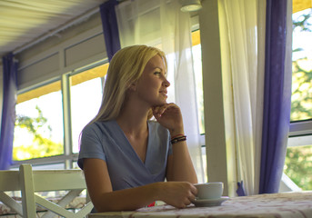 Girl drinks coffee or tea in cafe or restaurant.