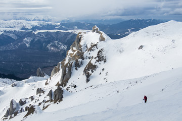 Fototapeta na wymiar Lonely hiker descending snowy mountain slope
