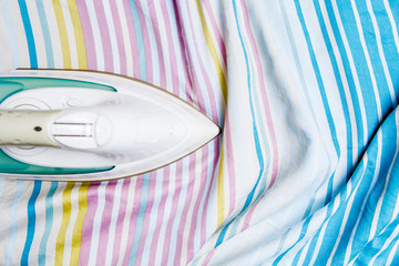 Photo of iron on striped sheet in house