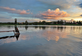 The genre photo was taken in July 2012 .Filmed the sunset on the lake.Against the backdrop of the Setting sun reflected clouds on the water, a bridge for catching fish from it.