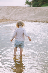 Adorable little girl walking at sandy beach