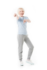 Smiling senior sportswoman standing and pointing by fingers isolated on white