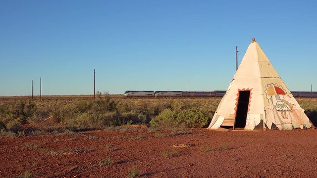 An Amtrak train travels fast past an American Indian teepee in the desert southwest.