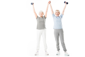 Obraz premium Senior sportswomen with arms up holding dumbbell isolated on white