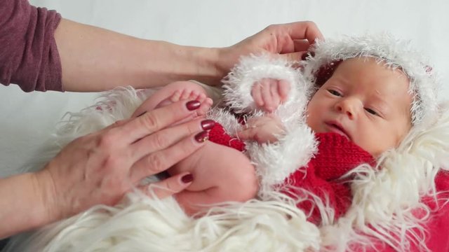 Tiny baby dressed as Santa Claus lying in the child's basket with his eyes open