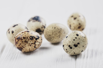 Naklejka na ściany i meble six quail eggs on a white wooden surface. Close up.